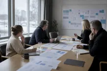Fem personer diskuterar dokument och färgade lappar runt ett mötesbord